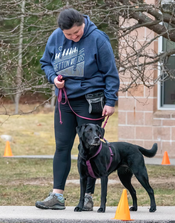 Emily working outdoors with a black Labrador on a leash